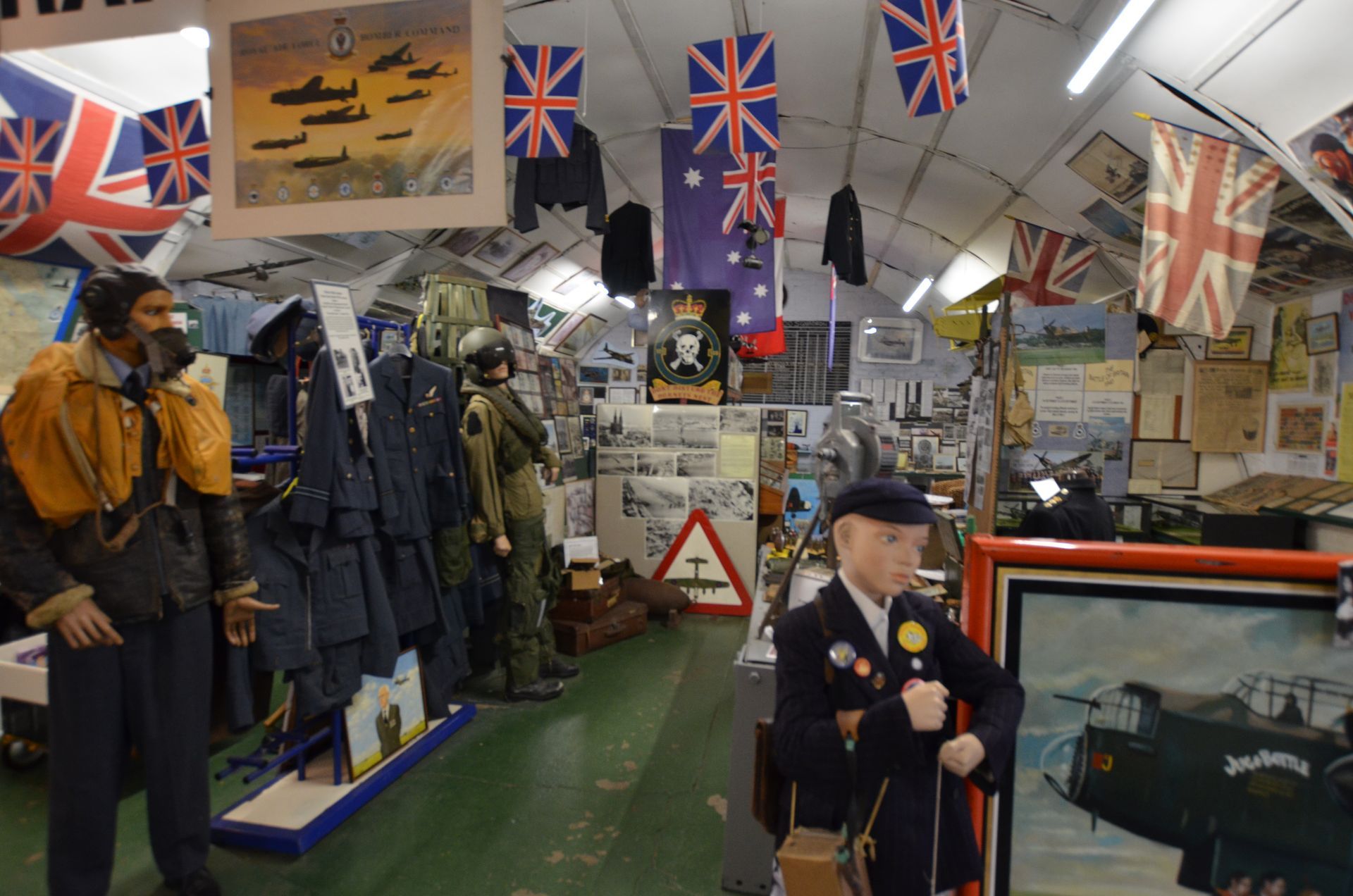 A boy is standing in front of a picture of a plane in a museum.