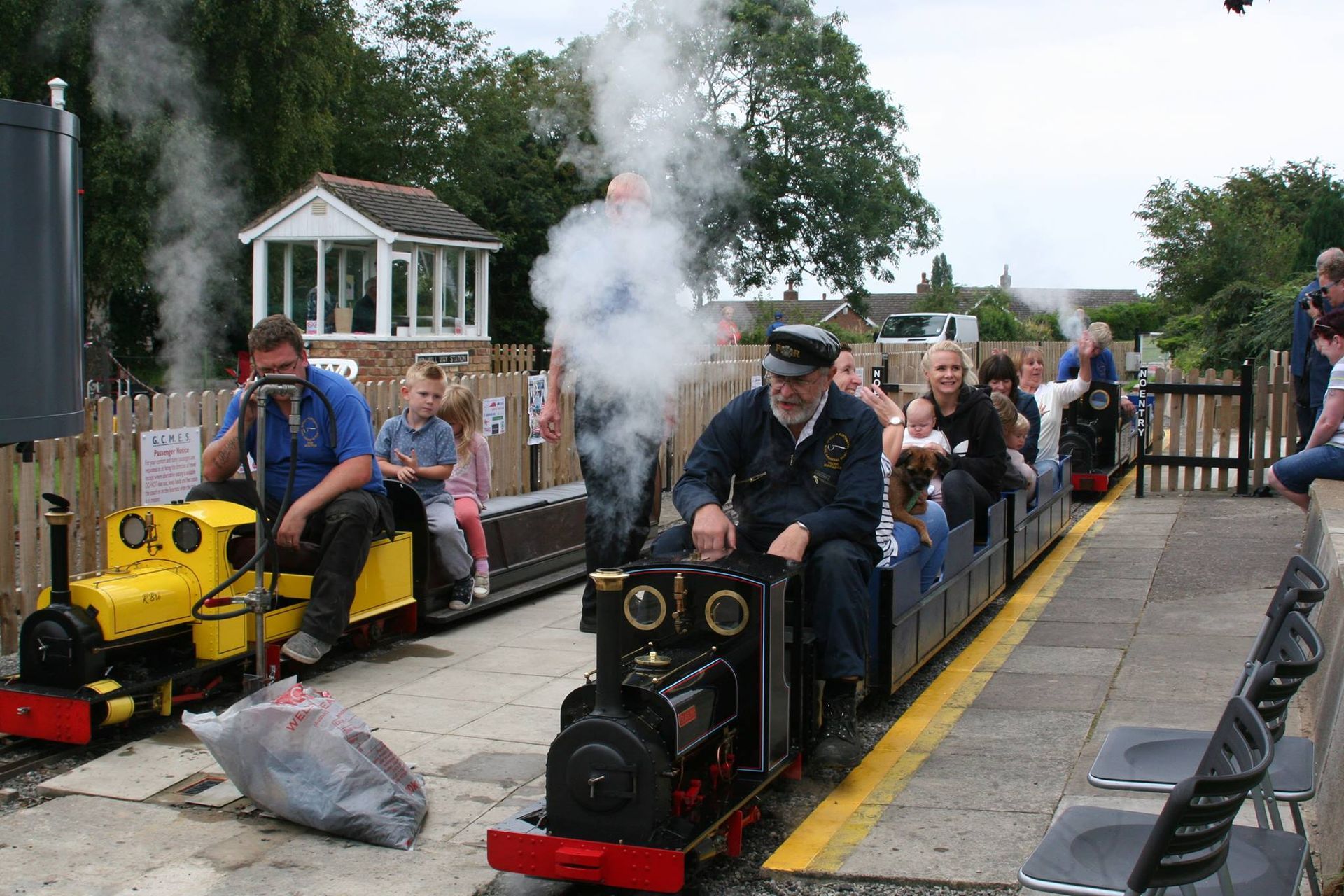A man is driving a small train with smoke coming out of it.