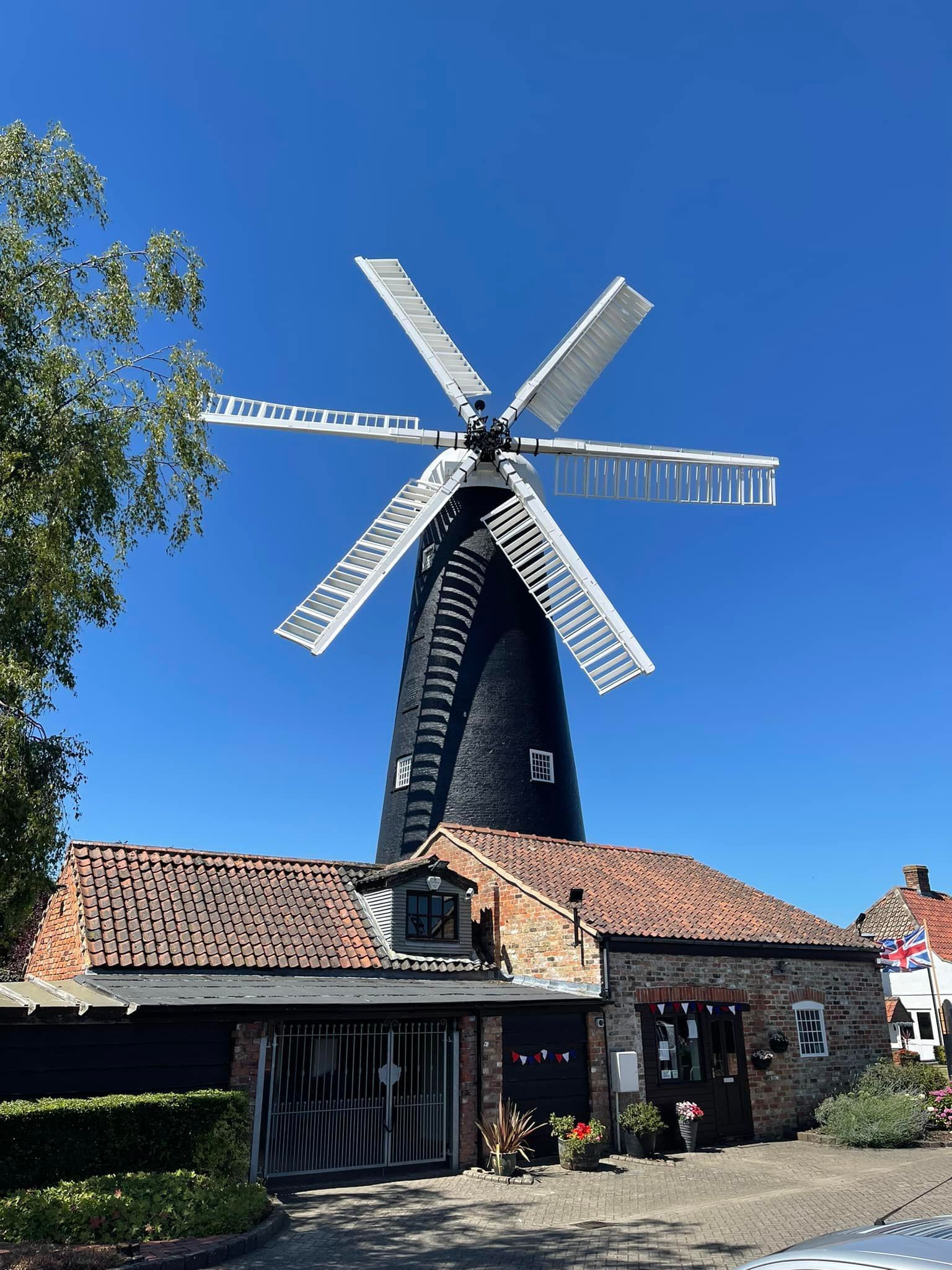 A large windmill is sitting on top of a brick building.