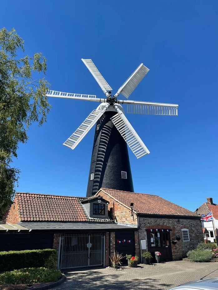 A large windmill is sitting on top of a brick building.