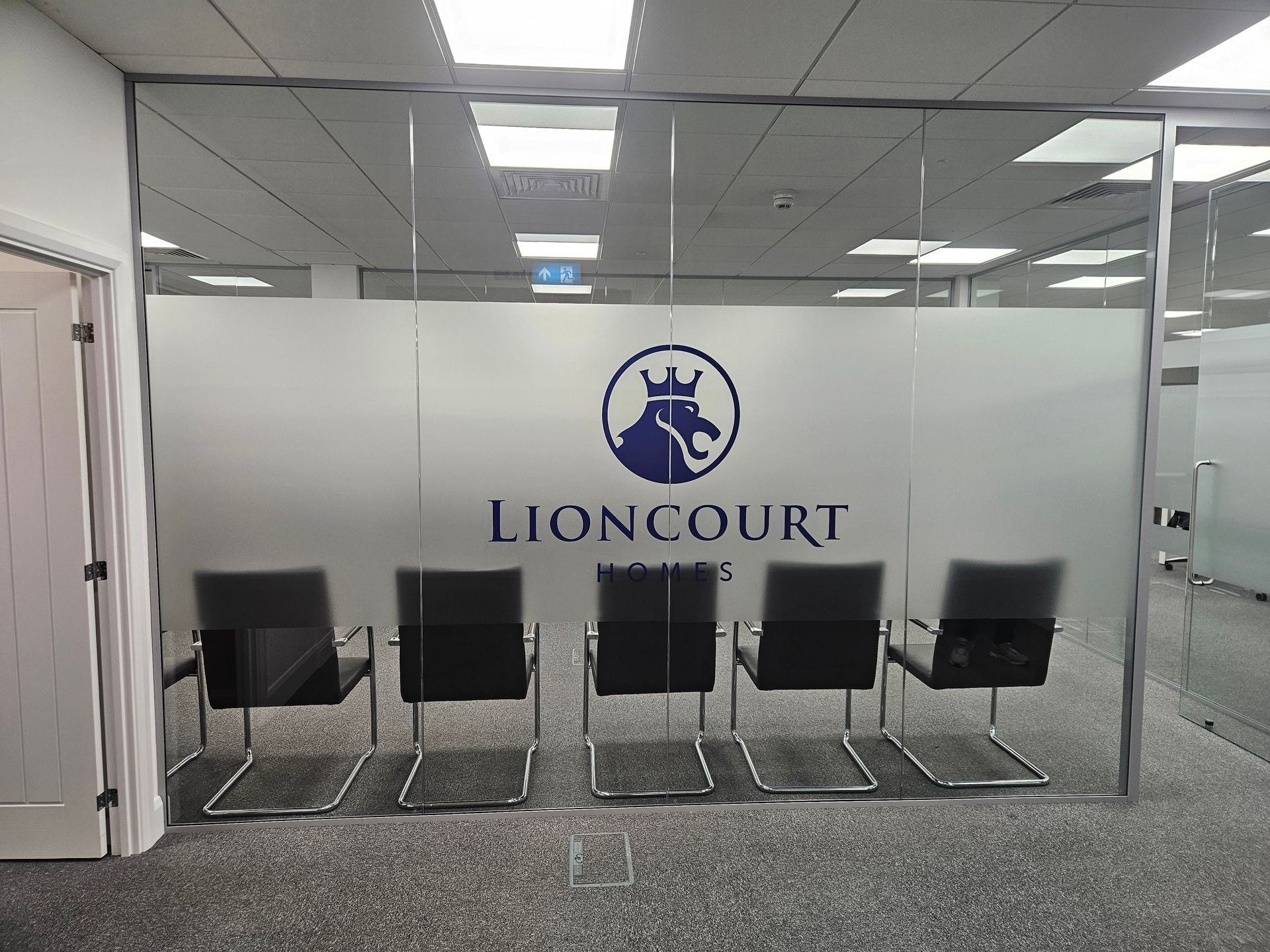 Office lobby with five black chairs facing a glass wall labeled “LIONCOURT.”
