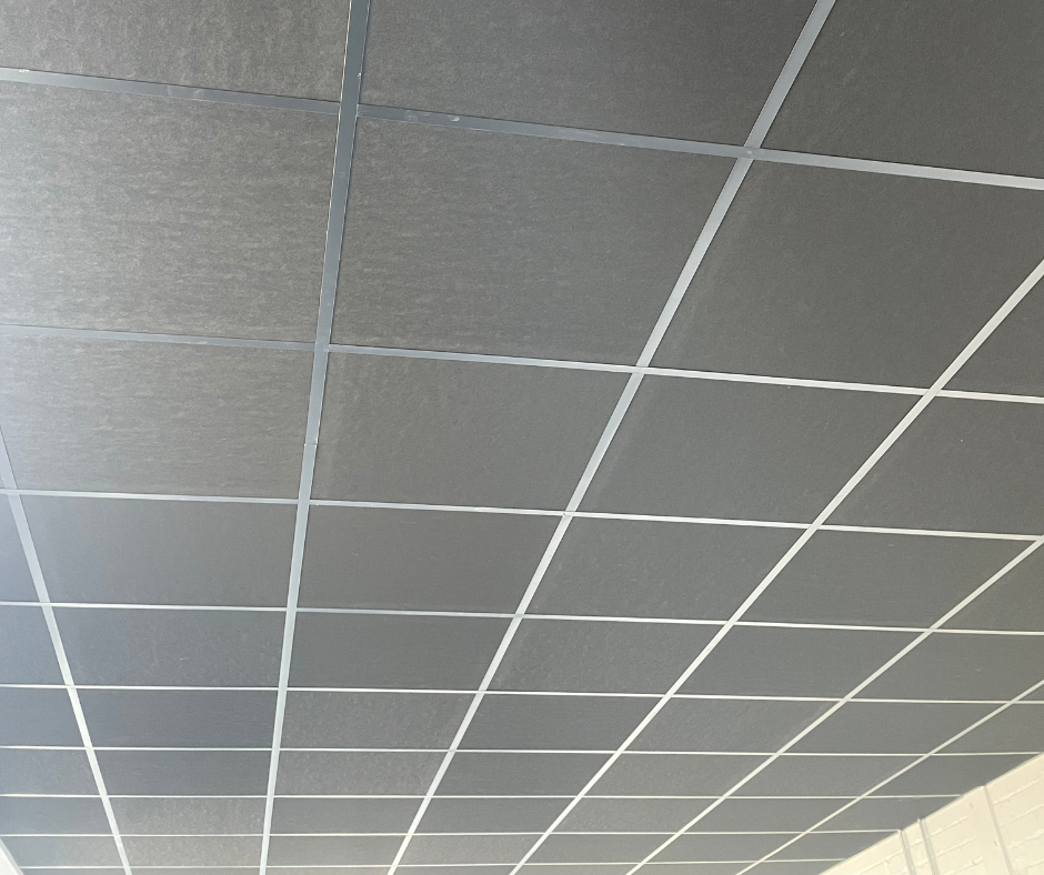 Gray drop ceiling with white grid tiles, viewed from below in a room
