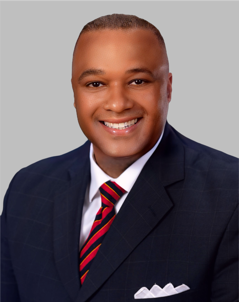 A man in a suit and tie is smiling in front of a window