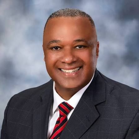 A man in a suit and tie is smiling in front of a window