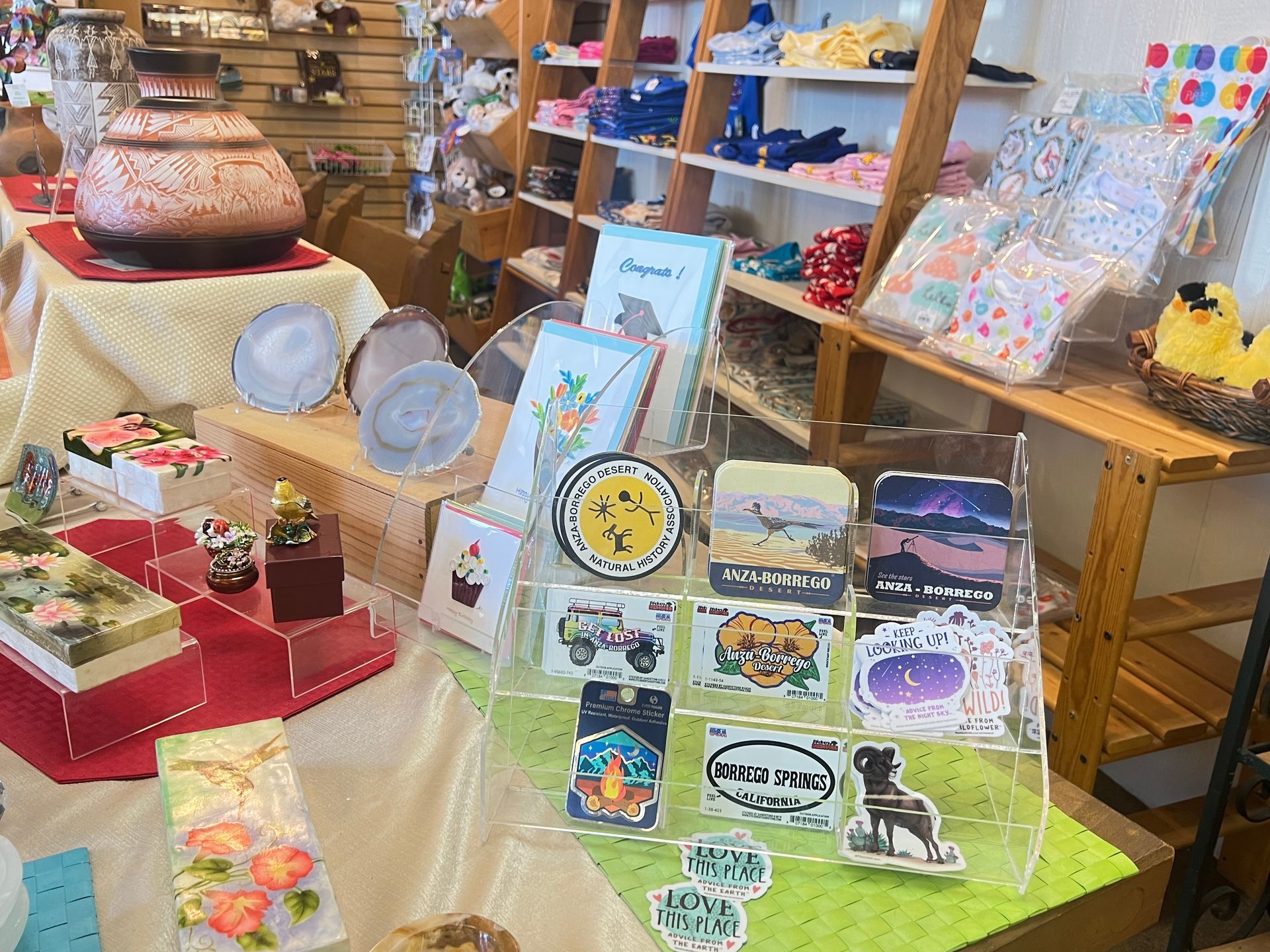 Craft market display with colorful handmade prints, ceramics, and embroidered goods on tables and shelves