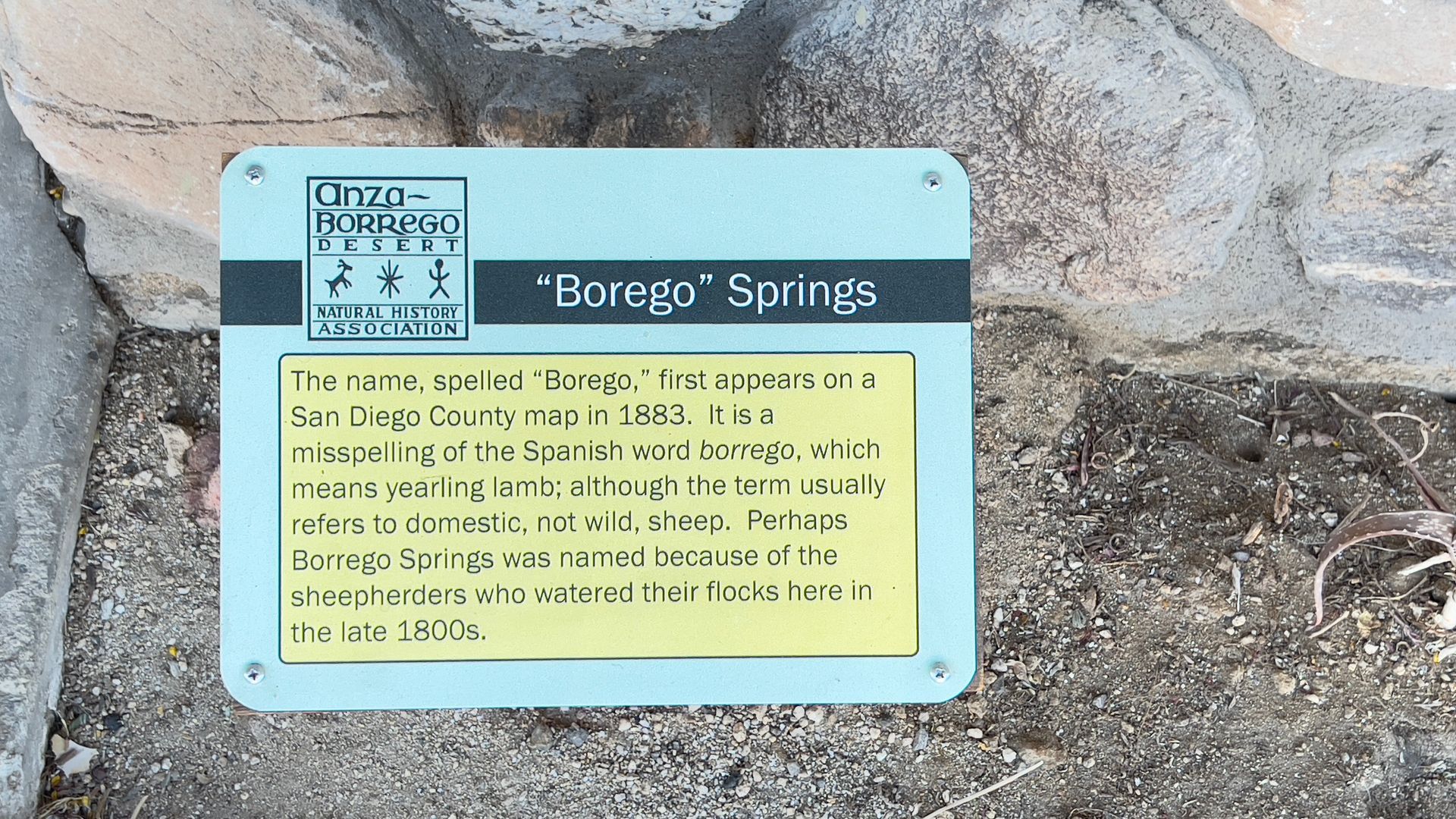 Blue informational sign for “Borego Springs” mounted on a rocky wall.
