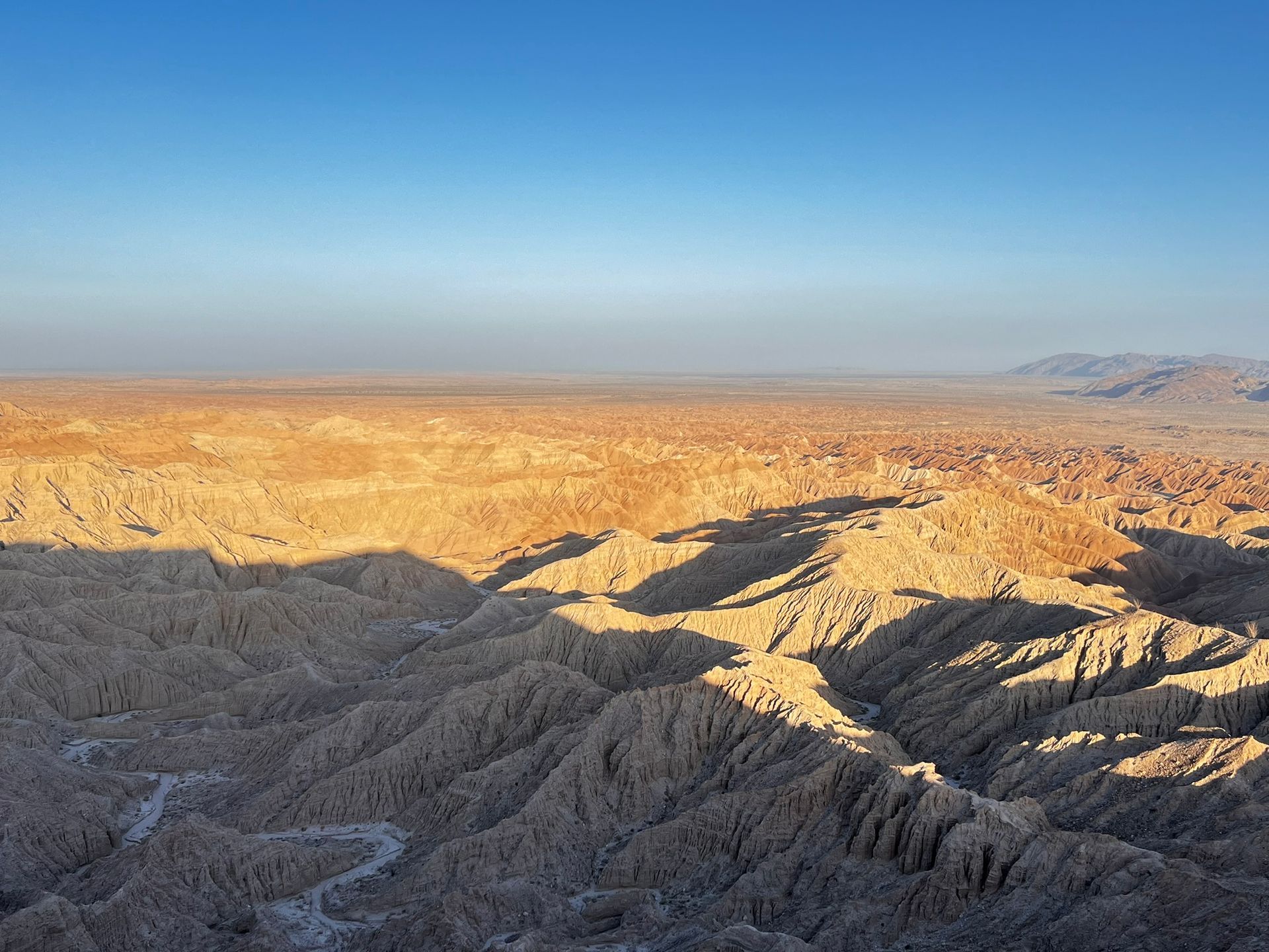 Sunlit desert canyon landscape with layered rocky ridges under a clear blue sky