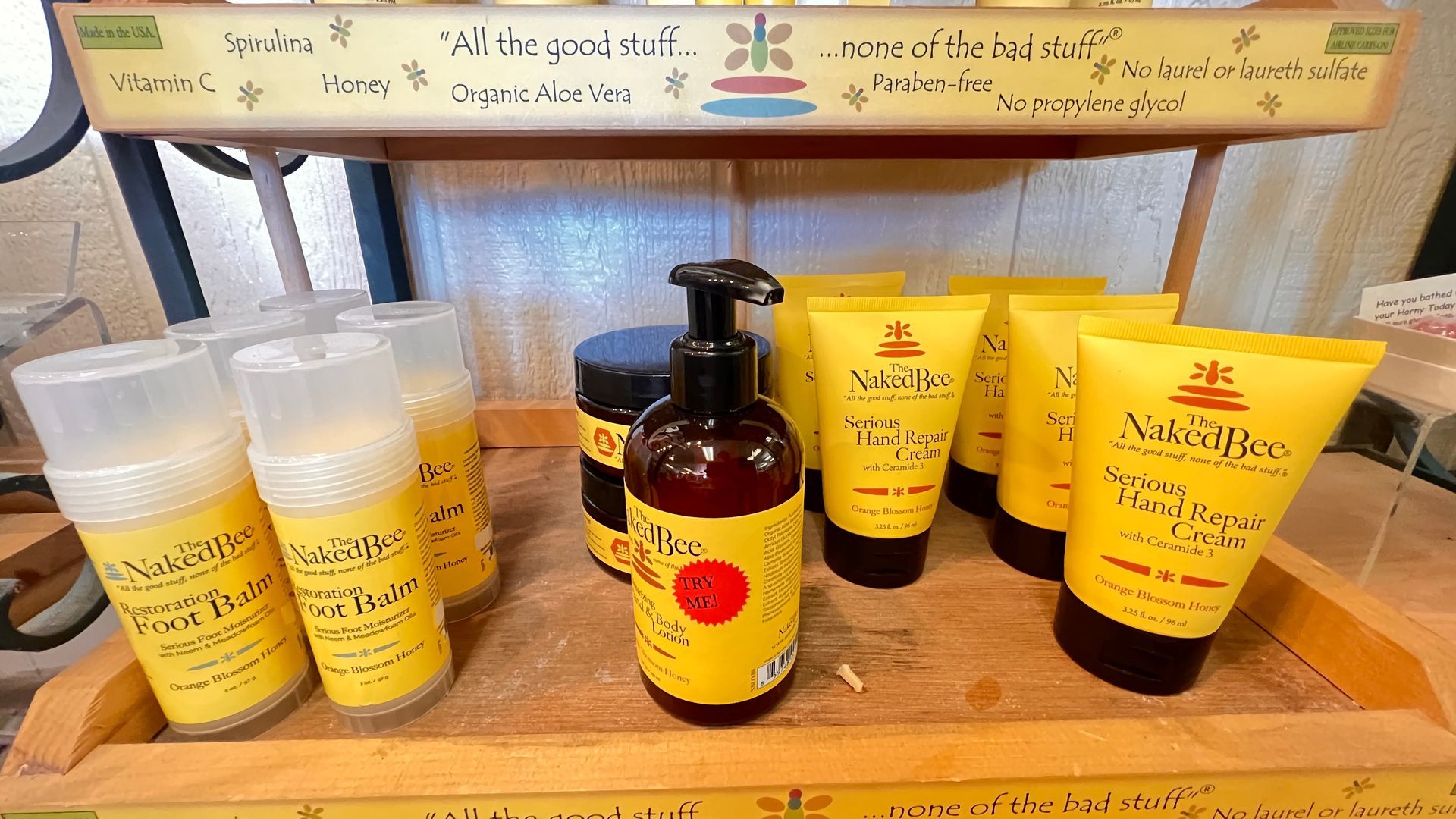A shelf of yellow skincare products, including creams, lotion bottles, and tubes, displayed neatly on a wooden counter.