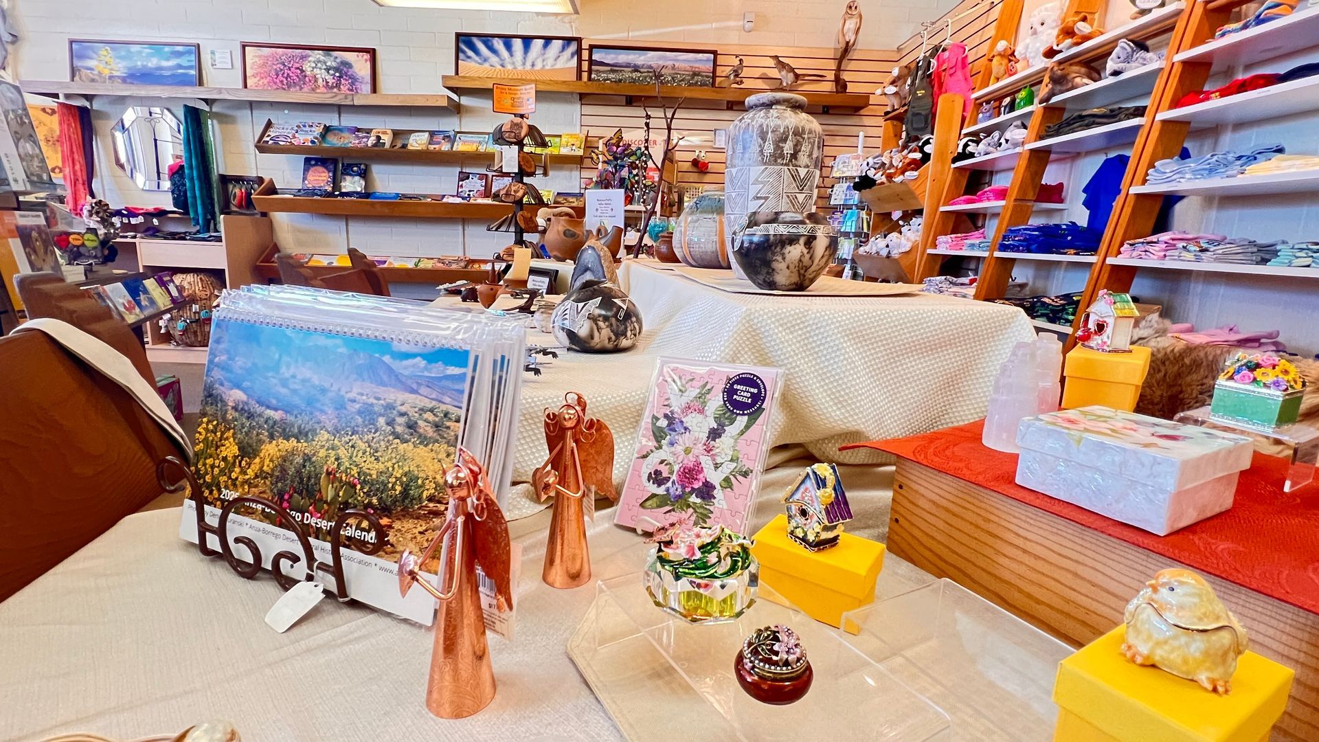 Colorful art and crafts shop with paintings, sculptures, and gift items displayed on shelves and tables