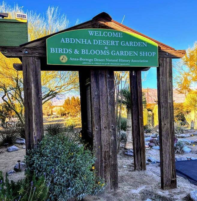 Welcome sign at Abdn. Aseert Garden Birds & Blooms Garden Shop amid trees and landscape