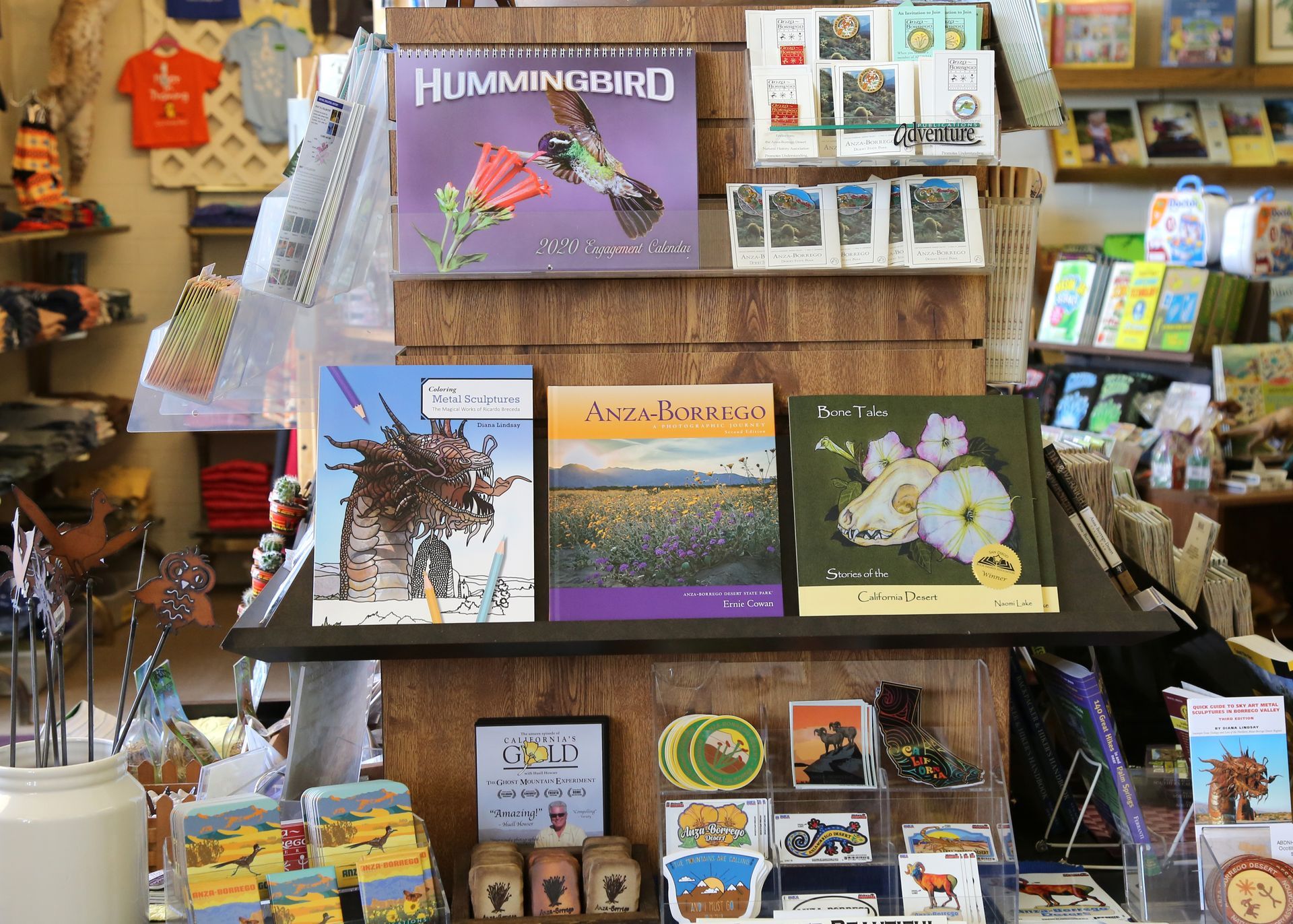 Art booth display of wildlife books, prints, and postcards on shelves and table racks