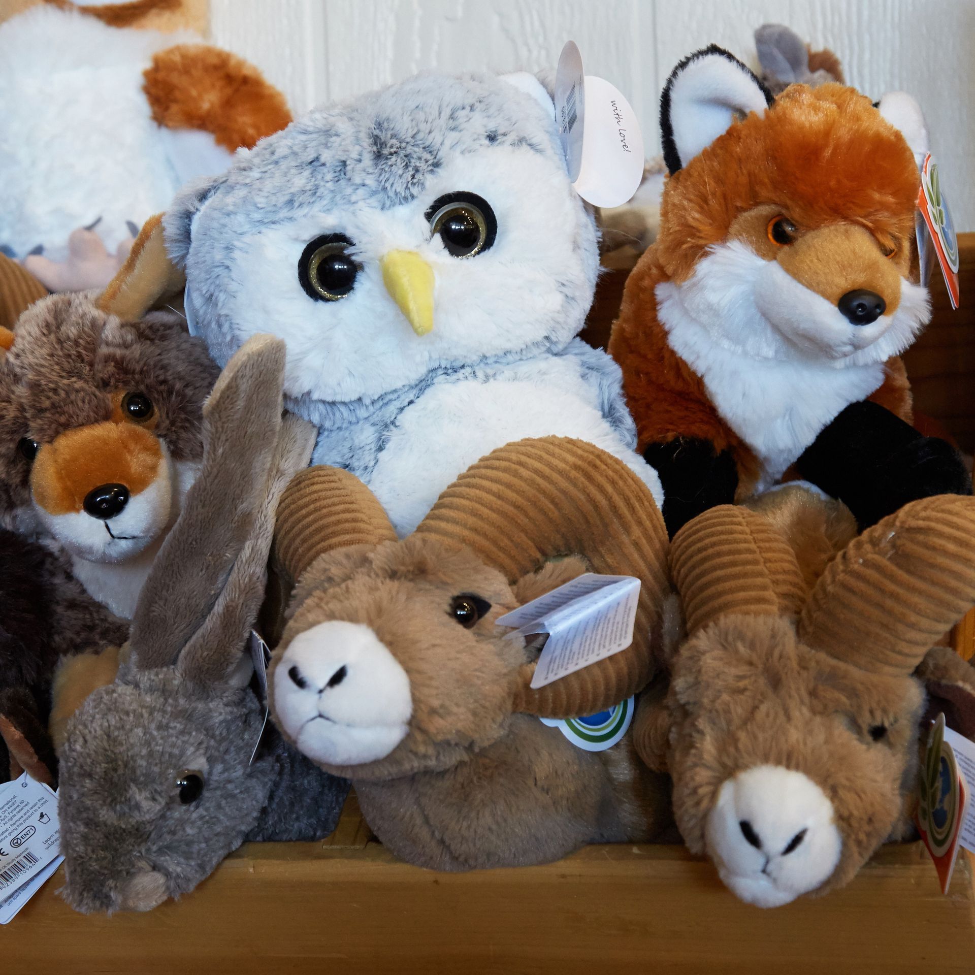 Stuffed animal display with foxes, owls, rabbit, and ram plush toys on a shelf.
