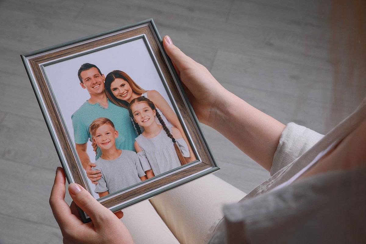 A Woman Is Holding a Picture of Her Family in A Frame — The Framer In Taree, NSW