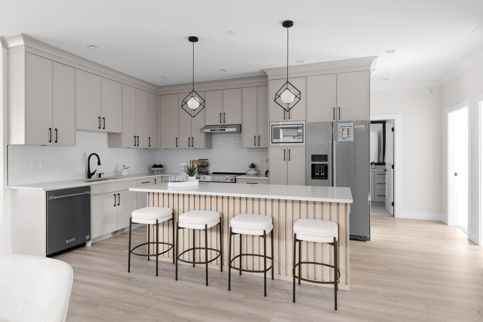 Modern kitchen with gray cabinets, island seating, pendant lights, and stainless steel appliances
