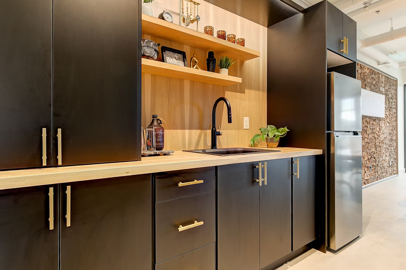 Modern kitchen with dark cabinets, wood shelves, sink, and stainless steel refrigerator