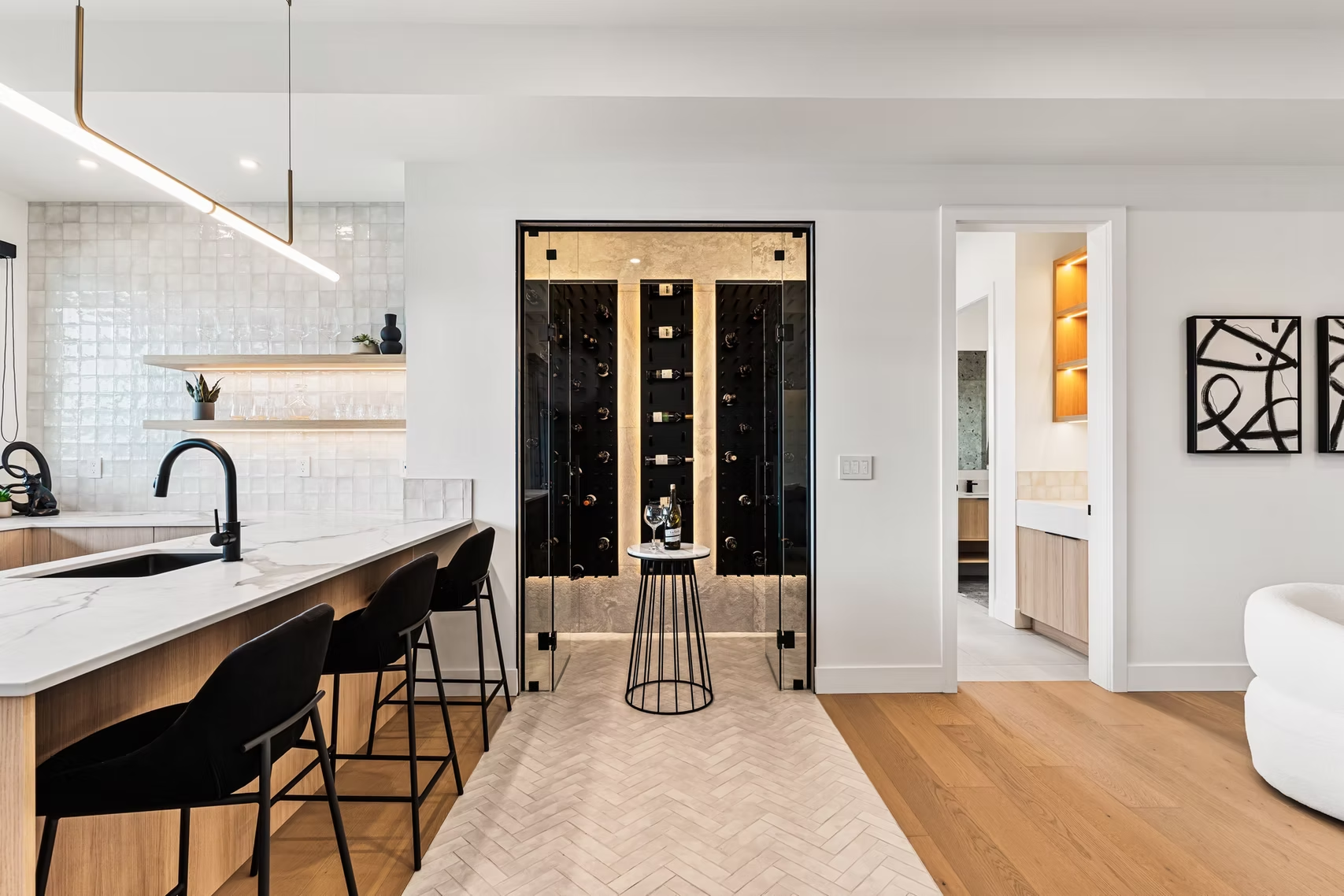 Modern kitchen and living area with island seating, black-framed glass doors, and light wood floors