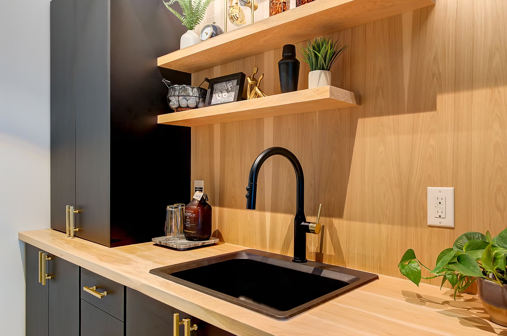 Modern kitchen sink with black faucet, wood shelves, and potted plants