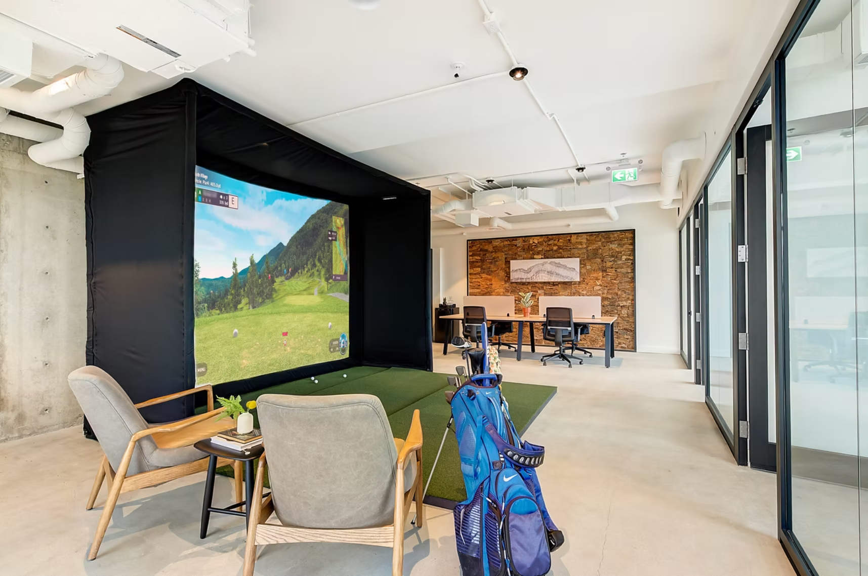 Modern lounge with chairs, bike, large wall screen, and glass-walled meeting area