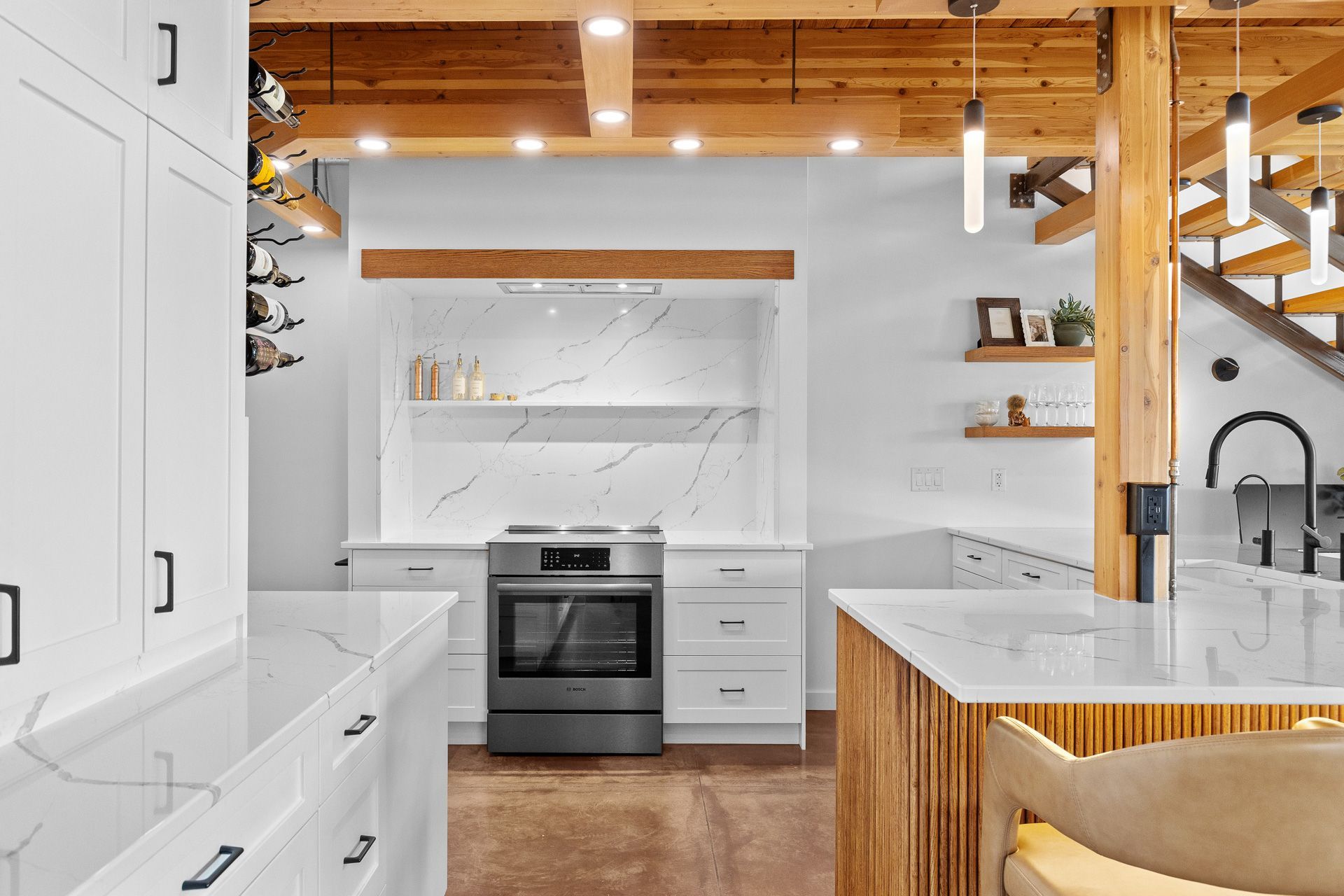 Bright modern white kitchen with marble counters, wood ceiling beams, and a black stove.