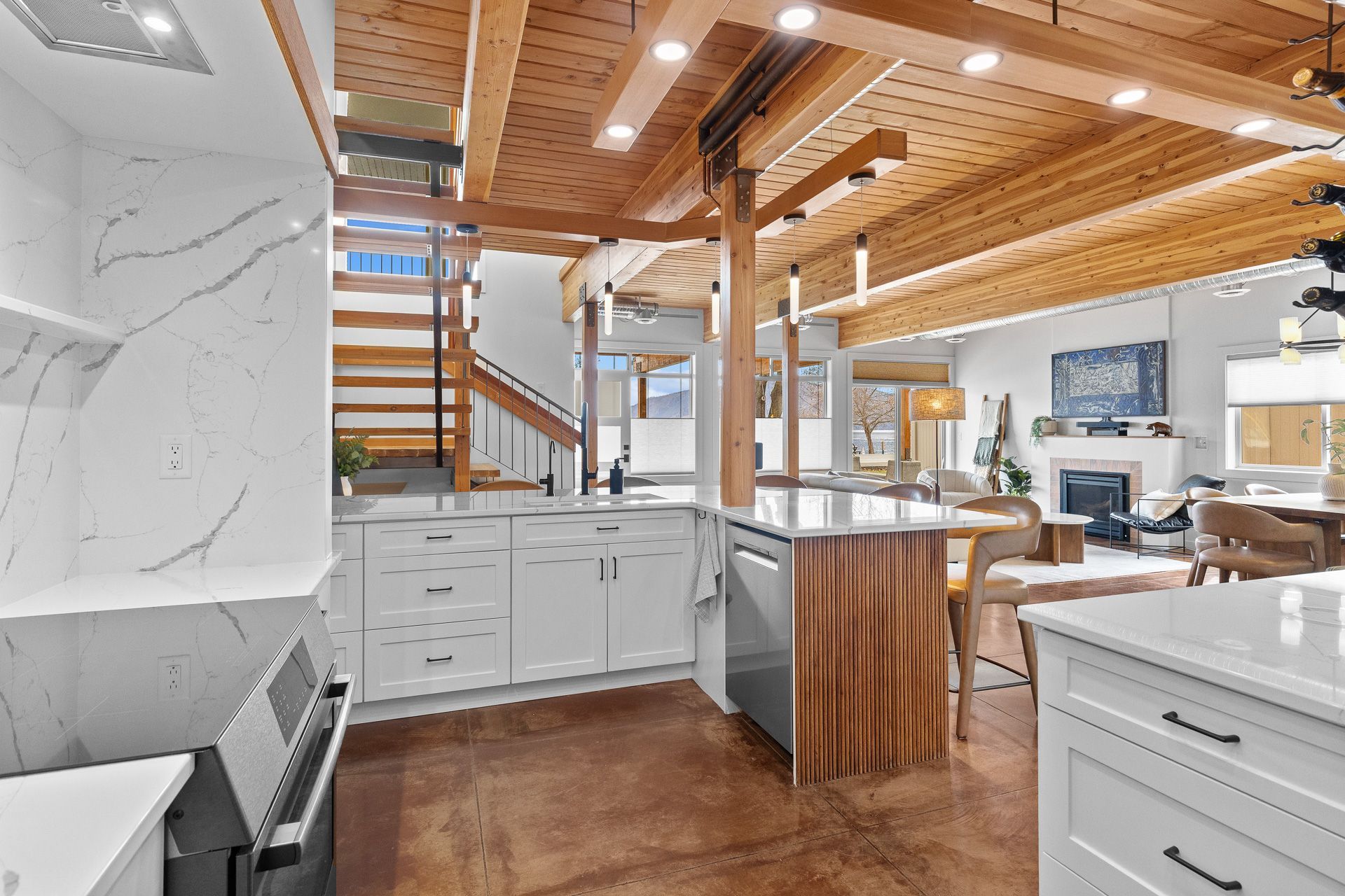 Modern kitchen with white cabinets, wood beams, marble island, and stainless steel appliances