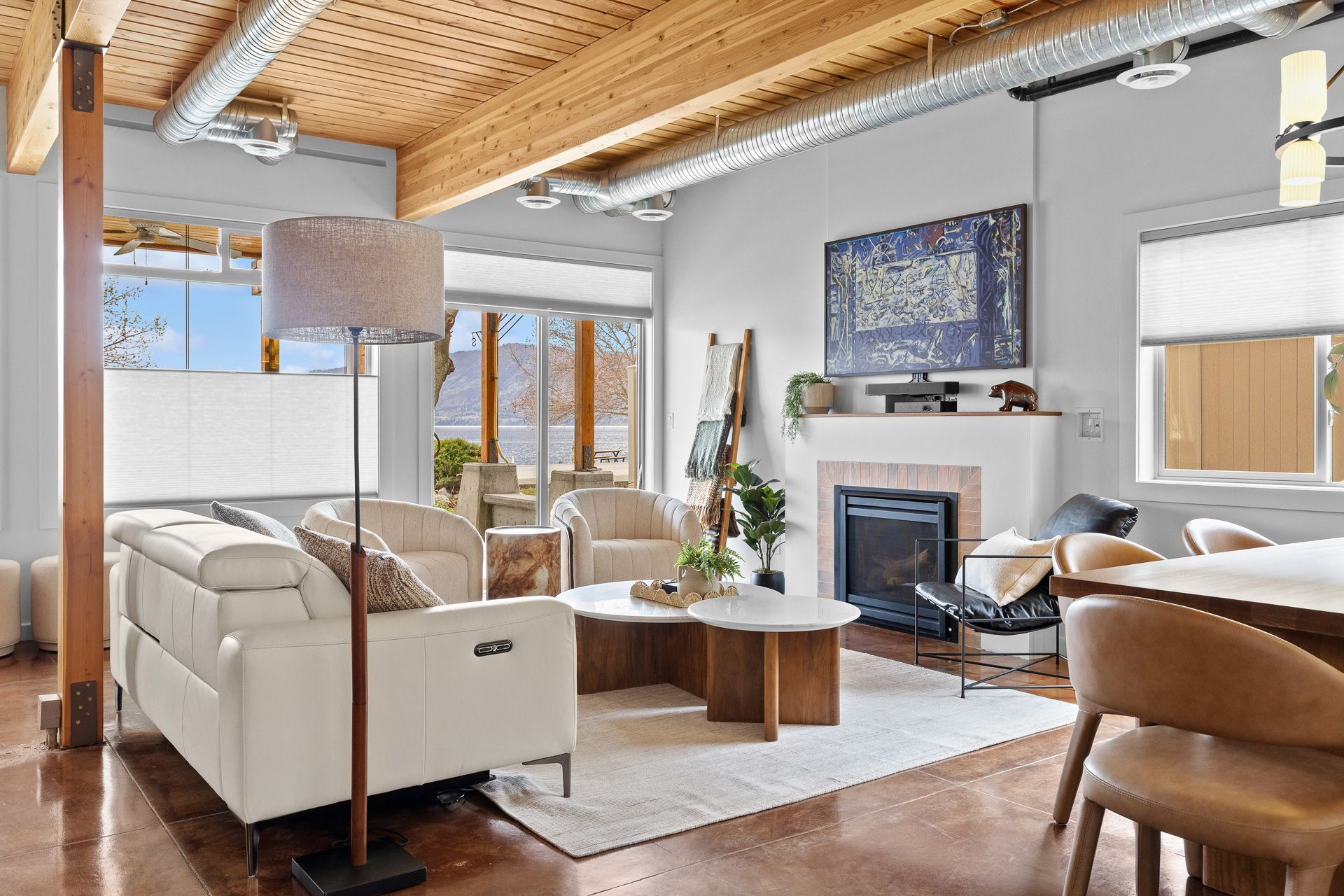 Modern living room with white sofa, fireplace, wood ceiling, and large windows