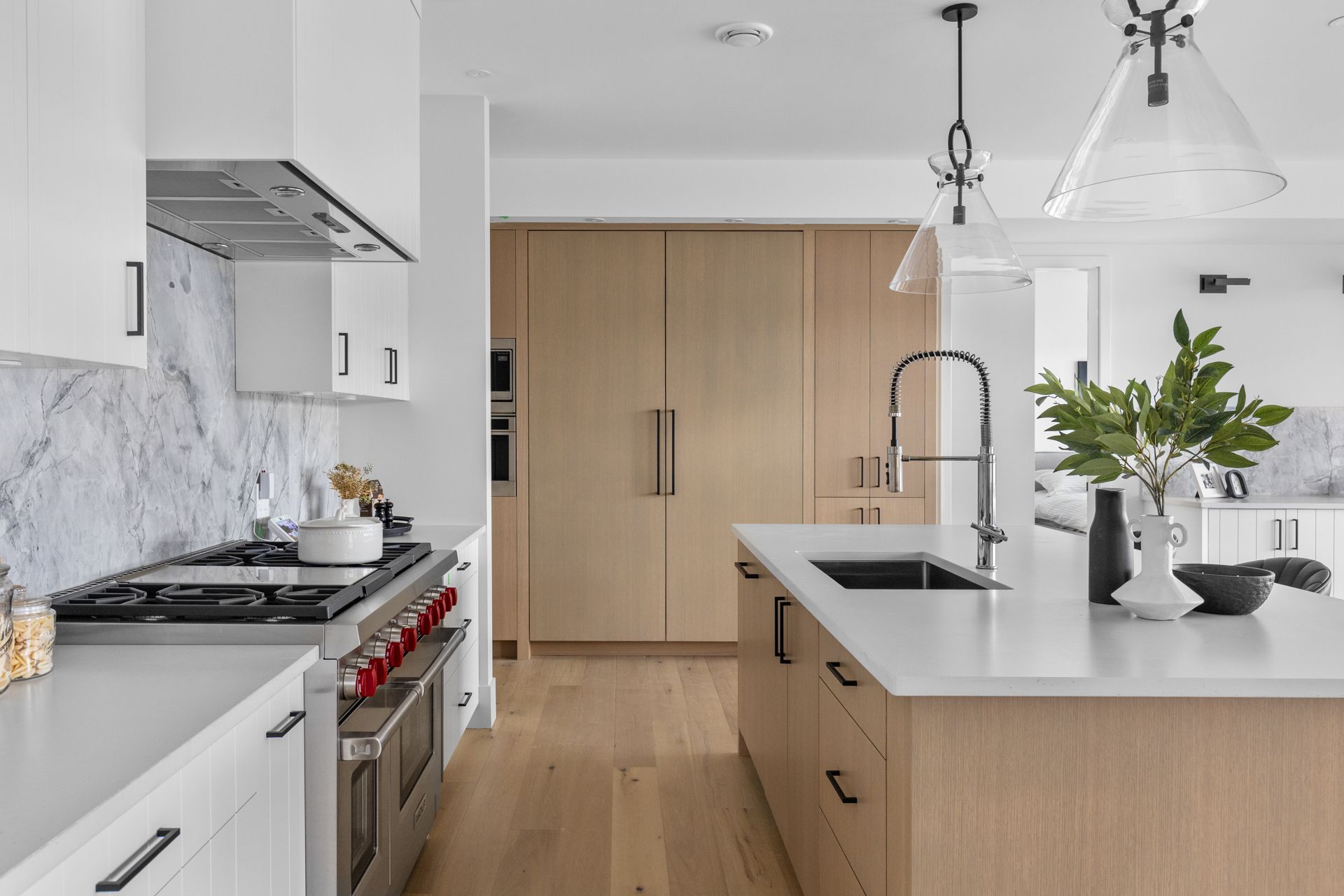 Bright modern kitchen with wood island, white cabinets, marble backsplash, and stainless-steel appliances