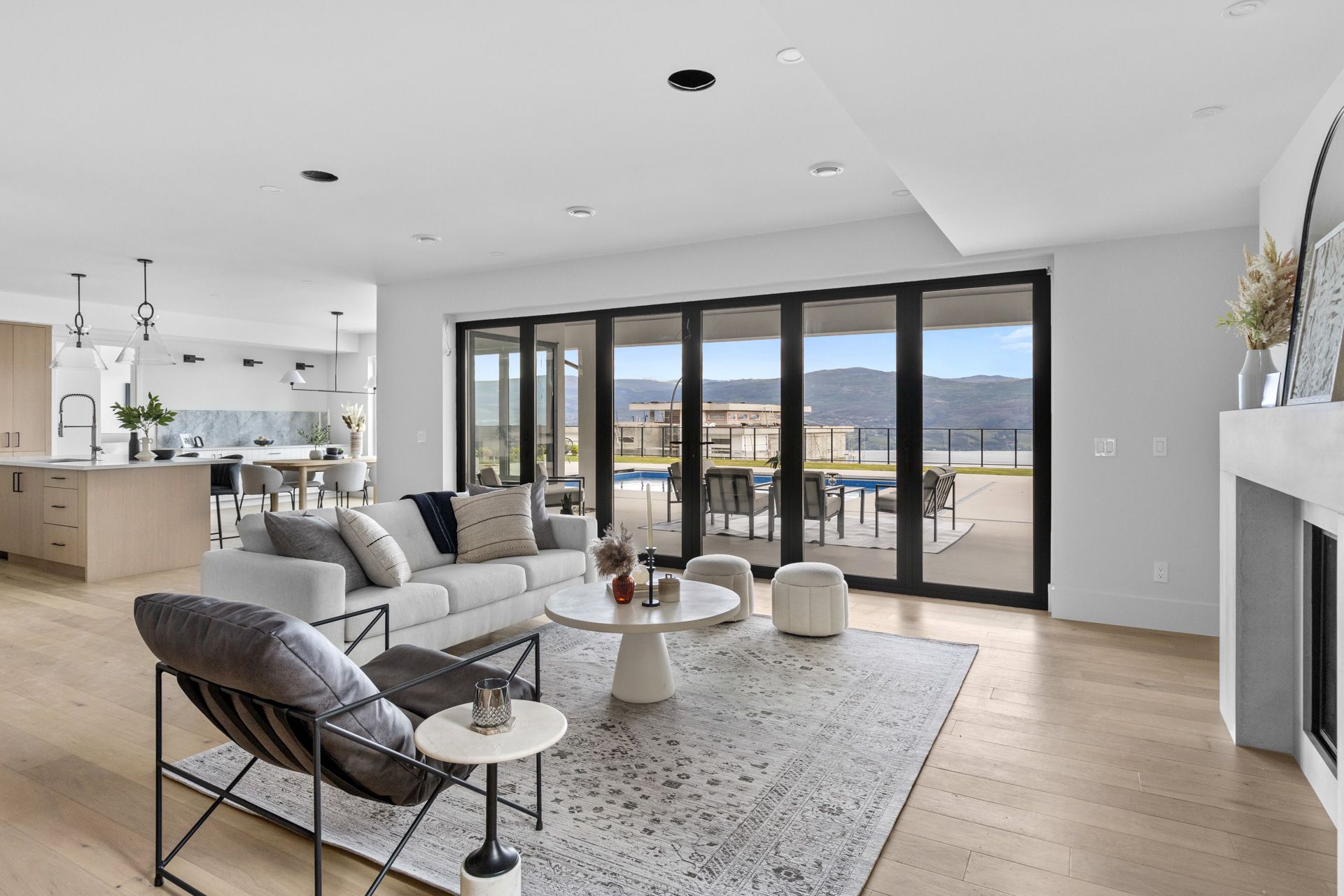 Modern living room with sectional sofa, lounge chair, rug, fireplace, and large glass doors overlooking a balcony