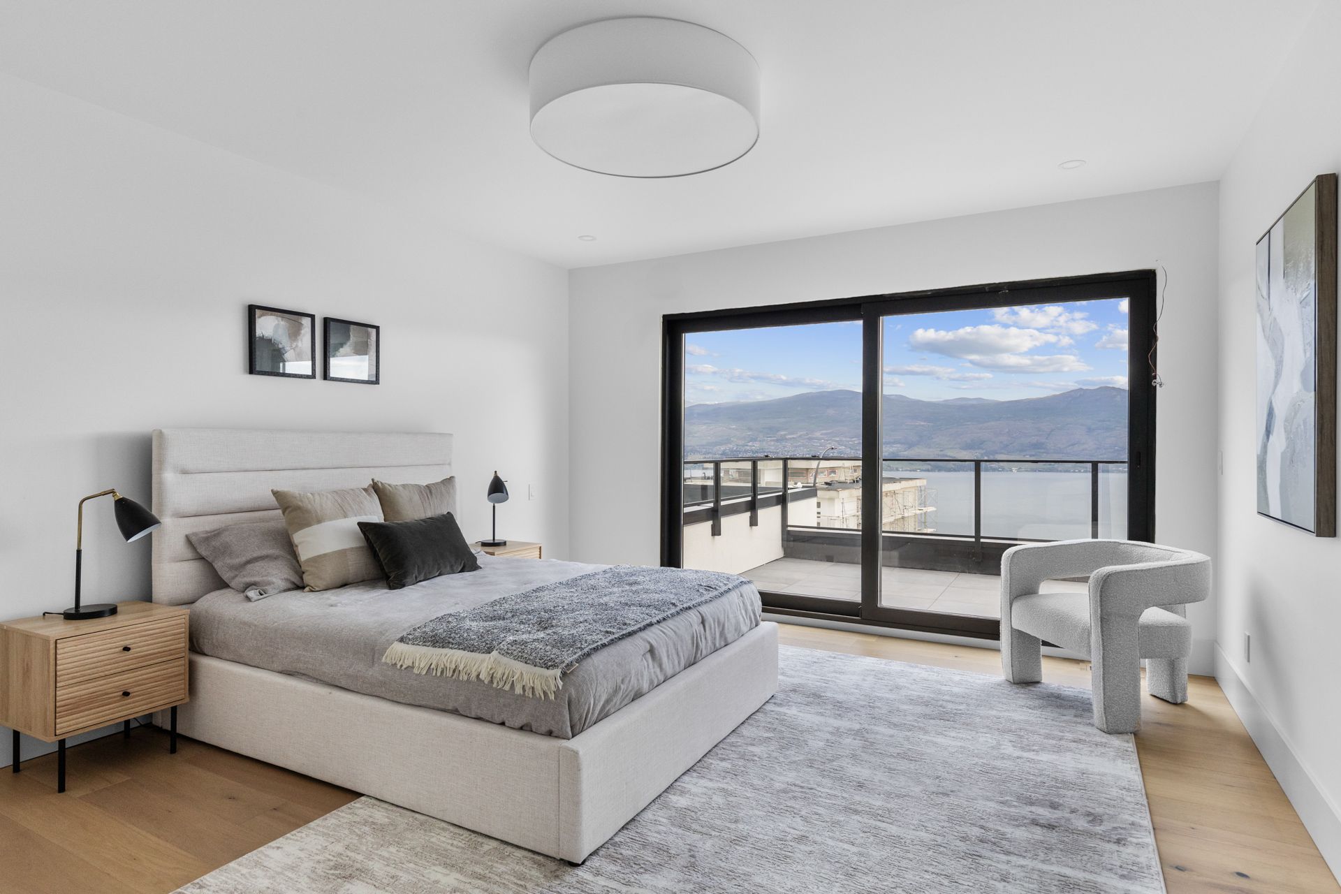 Bright modern bedroom with a large bed, floor-to-ceiling window, and mountain view