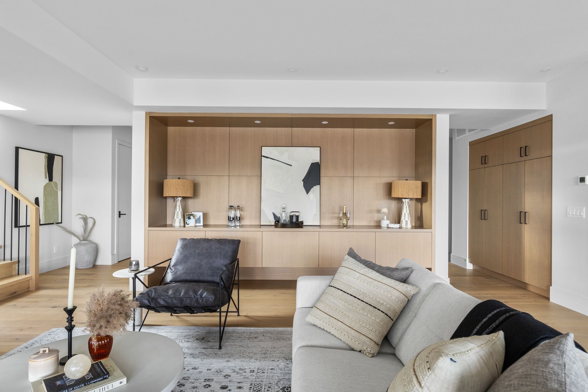 Modern living room with neutral decor, wood accent wall, gray sofa, lounge chair, and floor lamps