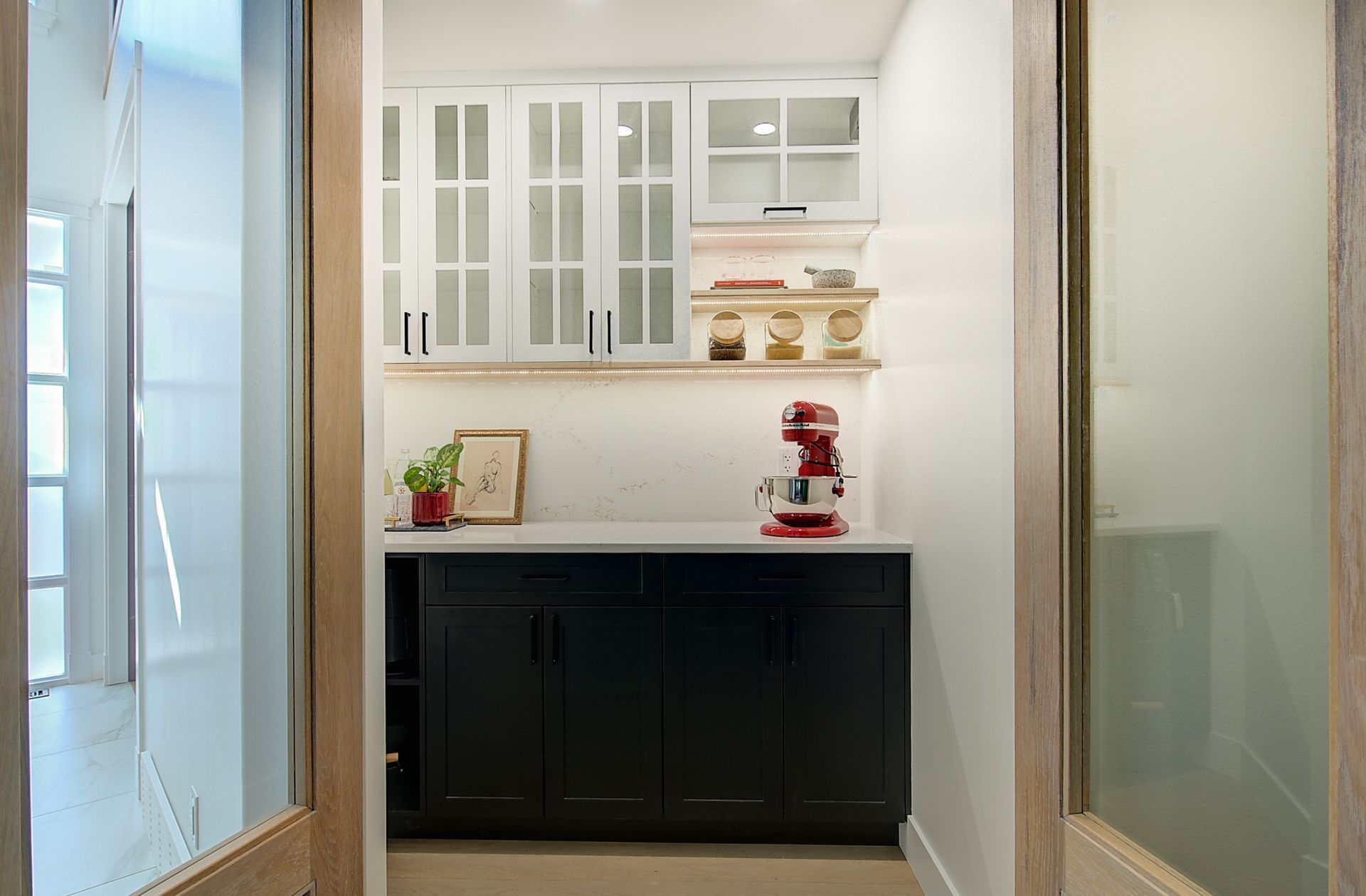 Modern kitchen nook with white cabinets, black lower cabinet, and a red stand mixer on the counter