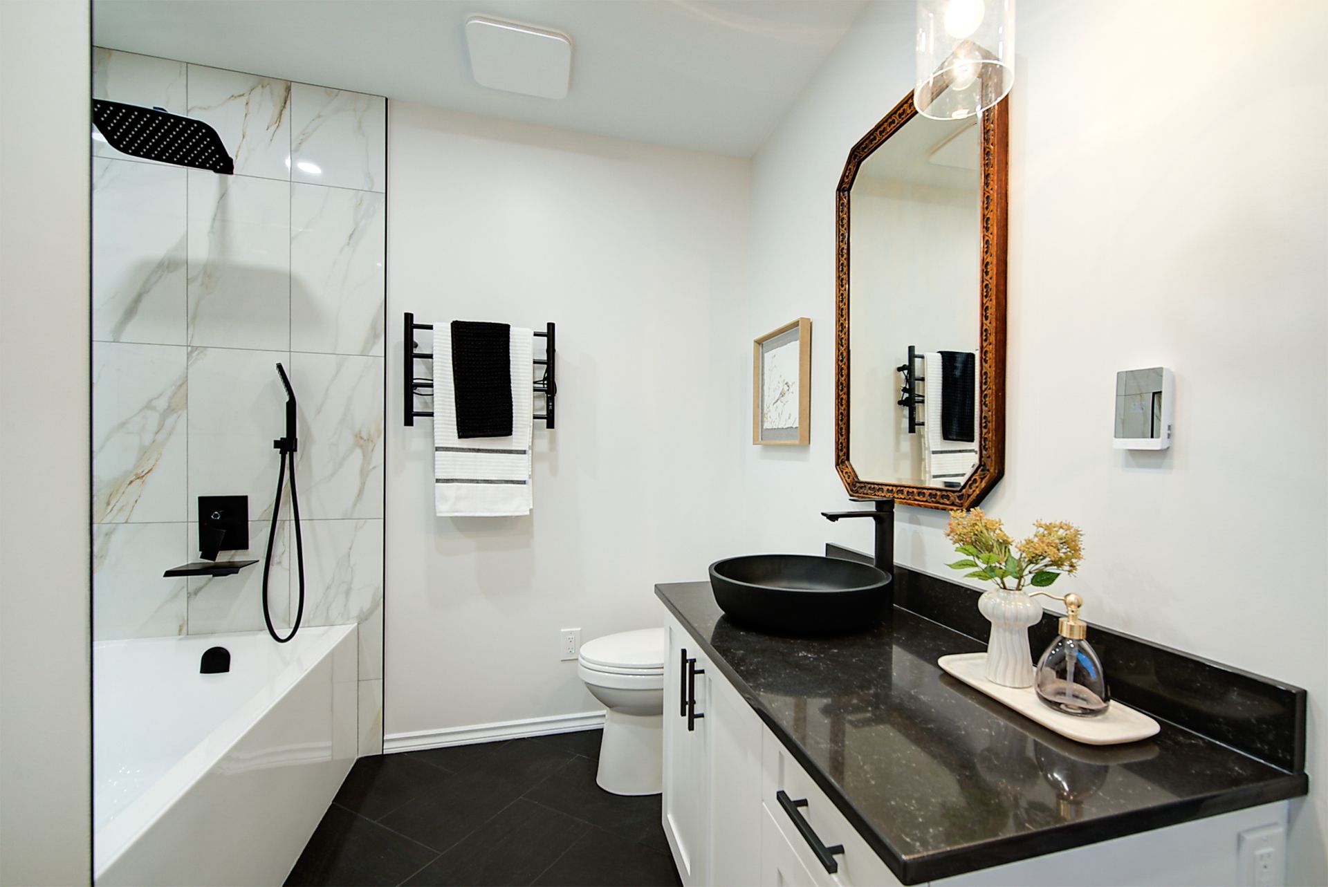 Modern bathroom with glass shower, black vanity, and gold-framed mirror