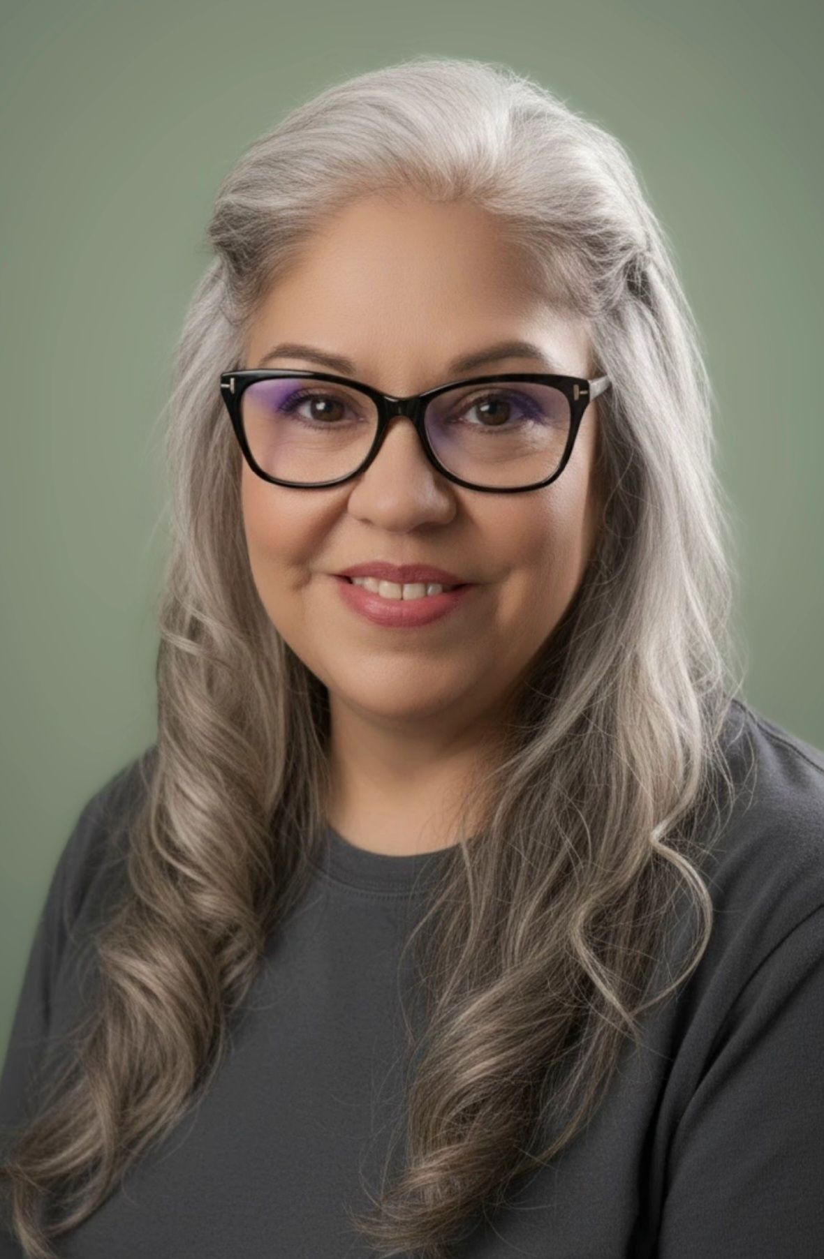 Close-up portrait of a person with glasses and a colorful rainbow headband, smiling slightly.