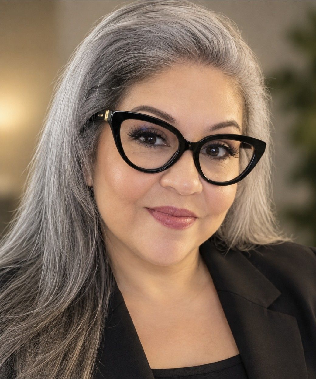 Close-up portrait of a person with glasses and a colorful rainbow headband, smiling slightly.