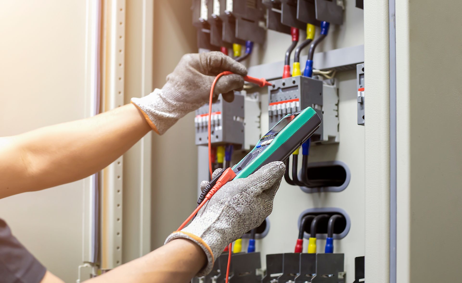 Electrical engineer testing electric control cabinet to ensure safe and efficient system operation.