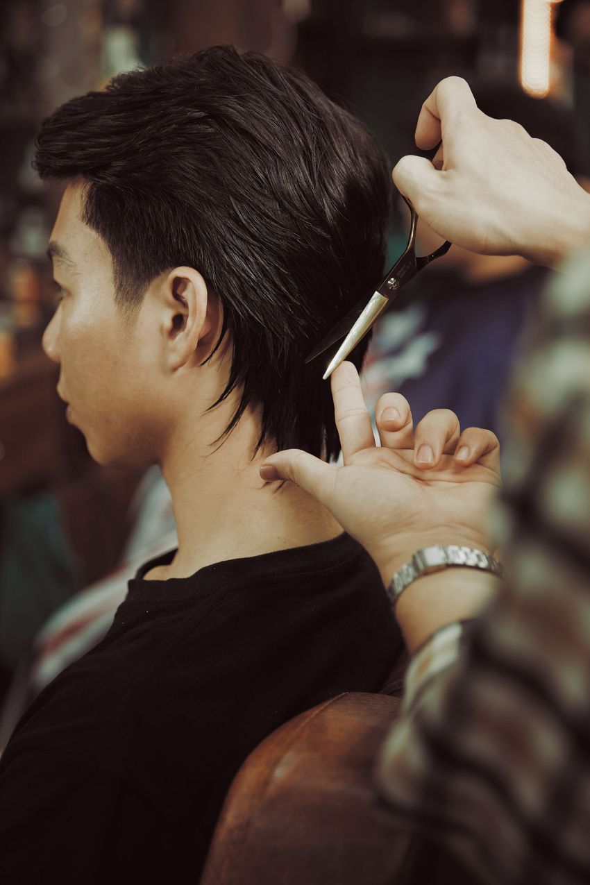 Person getting a haircut with scissors at a salon