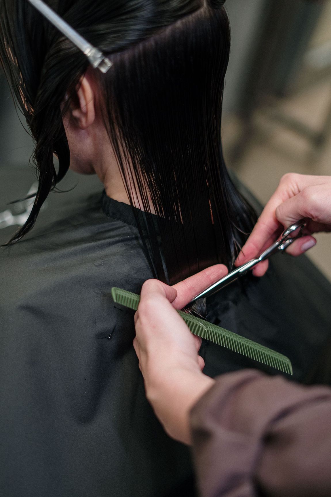 Barber trimming a client’s hair with scissors in a salon