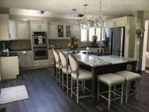Spacious kitchen with a large island, cream cabinets, stainless steel appliances, and dark flooring.
