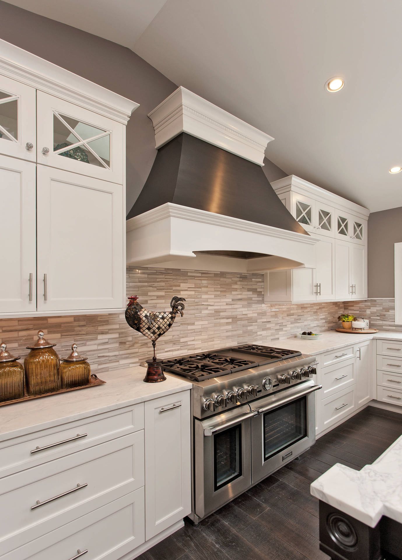 White kitchen with stainless steel appliances, stone backsplash, and dark wood floor.
