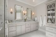 Bathroom with double vanity, two mirrors, and a linen cabinet. Soft gray cabinets, marble countertops, white walls.