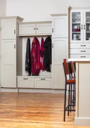 Mudroom with built-in storage and coat rack in a kitchen setting; light gray cabinets and wooden flooring.