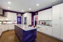 Bright purple and white kitchen with island and cabinetry.