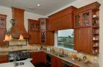 A kitchen with brown cabinets, stainless steel appliances, and a window overlooking a pool and lake.