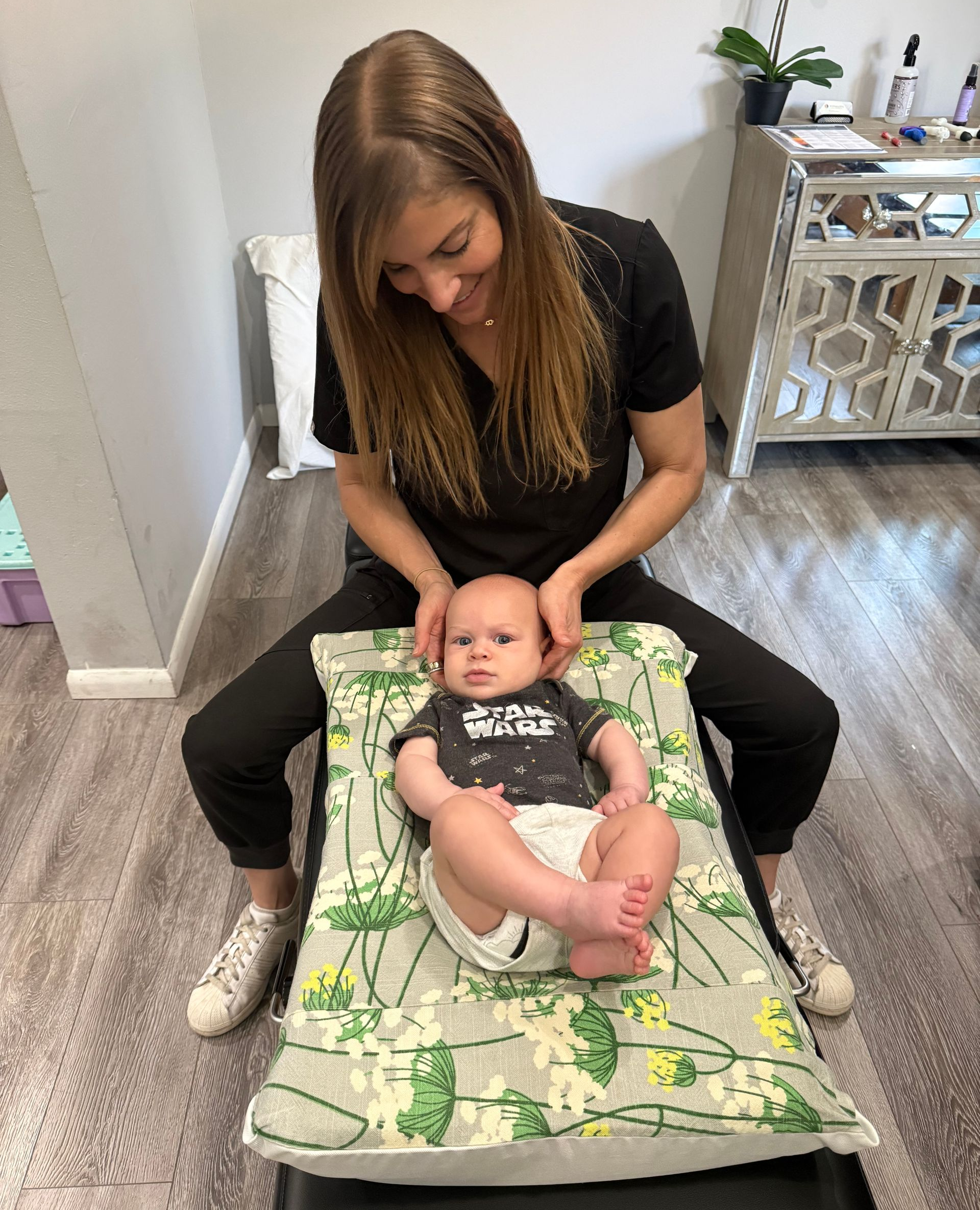 Chiropractor professional performing pediatric chiropractic on a baby.