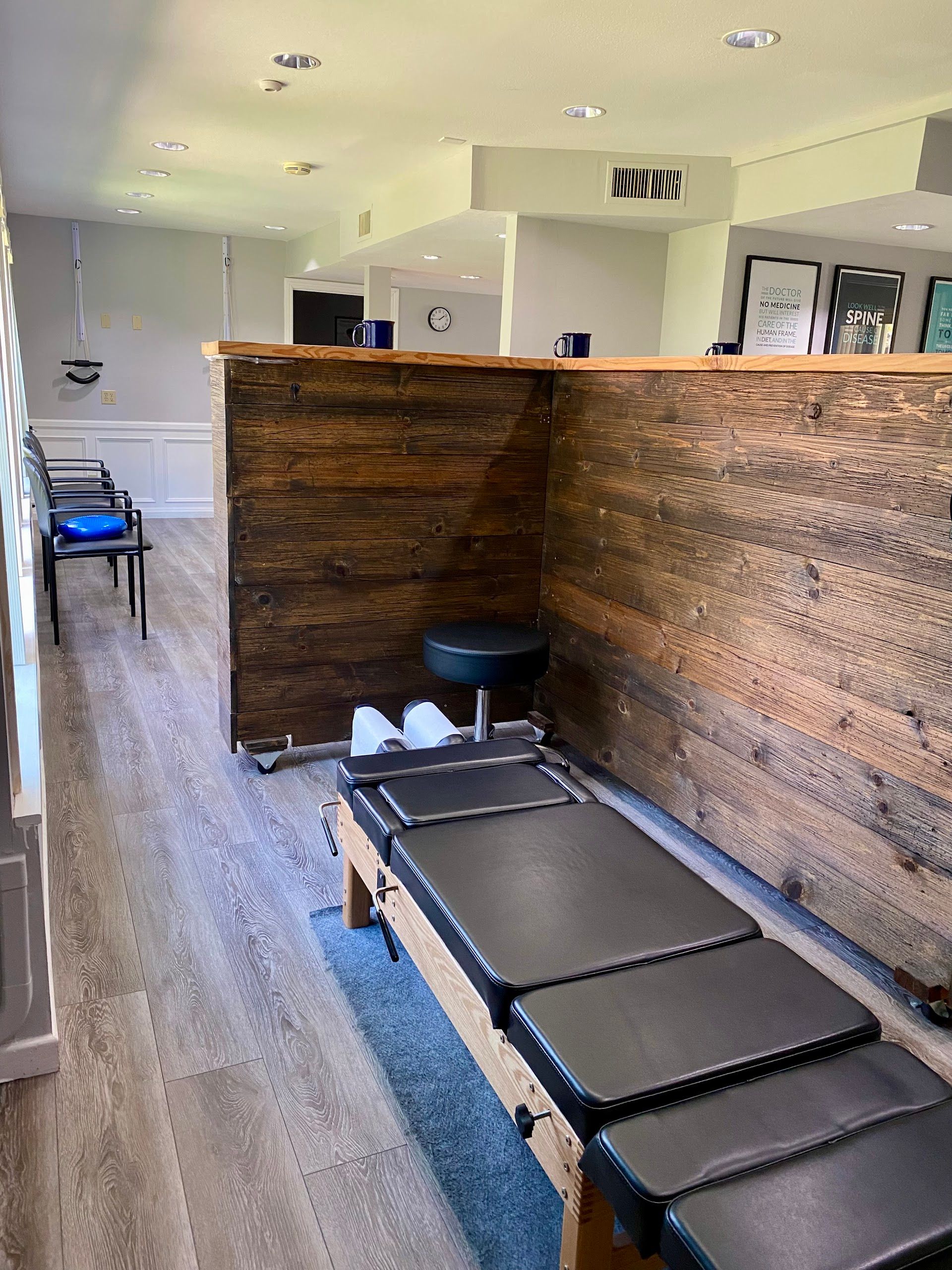 Home interior with a wooden divider, black bench seats, and a blue chair in a bright room.