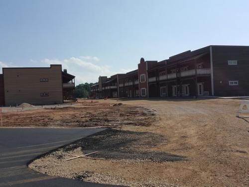 Partially built apartment complex with dirt lot and paved road under a clear sky