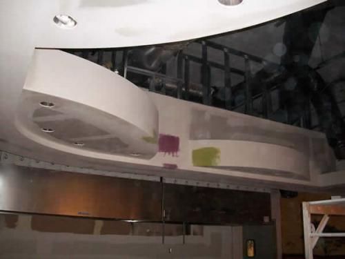 Modern interior with a curved white ceiling structure, glass wall, and wood paneling