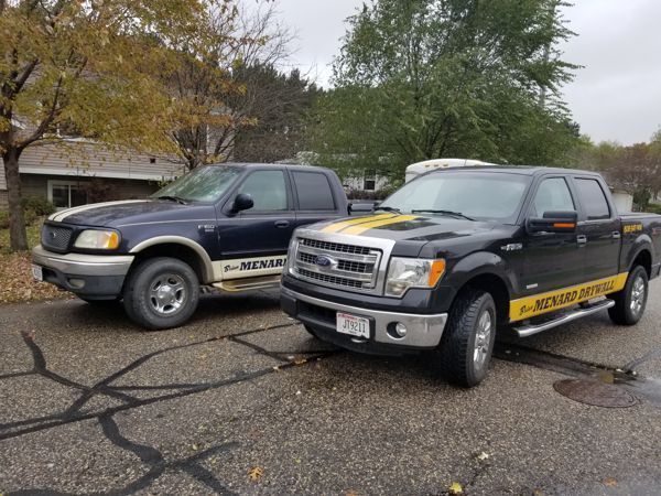 Two parked pickup trucks with police-style markings in a wet parking lot.