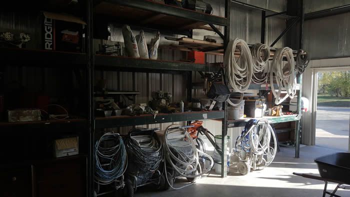 Shelves of coiled hoses and cables in a workshop, with bright daylight at the open doorway