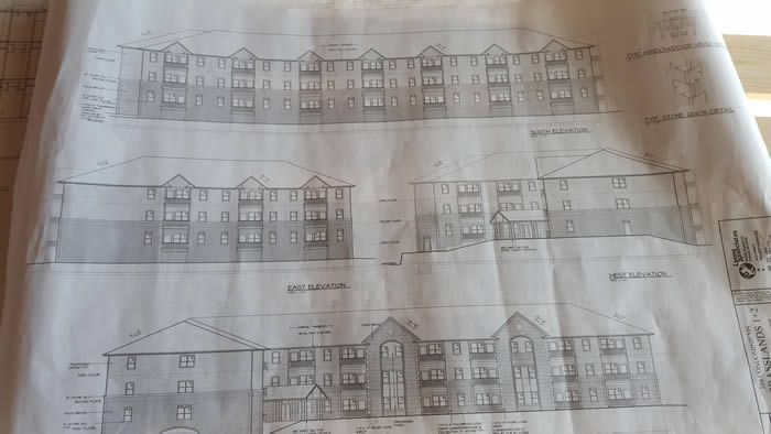 Blueprint-style drawings of a multi-unit apartment building facade on paper