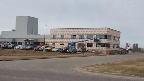 Multi-story office building and parking lot beside a road on an overcast day